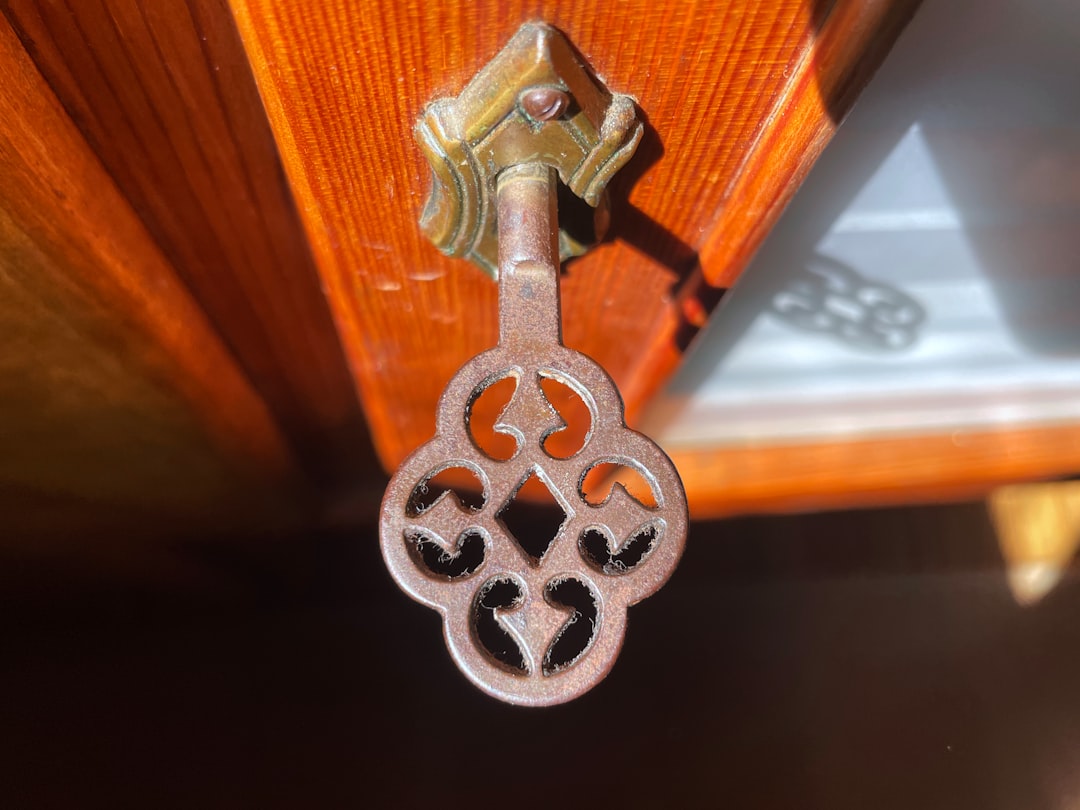 An ornate key hangs from a wooden surface.